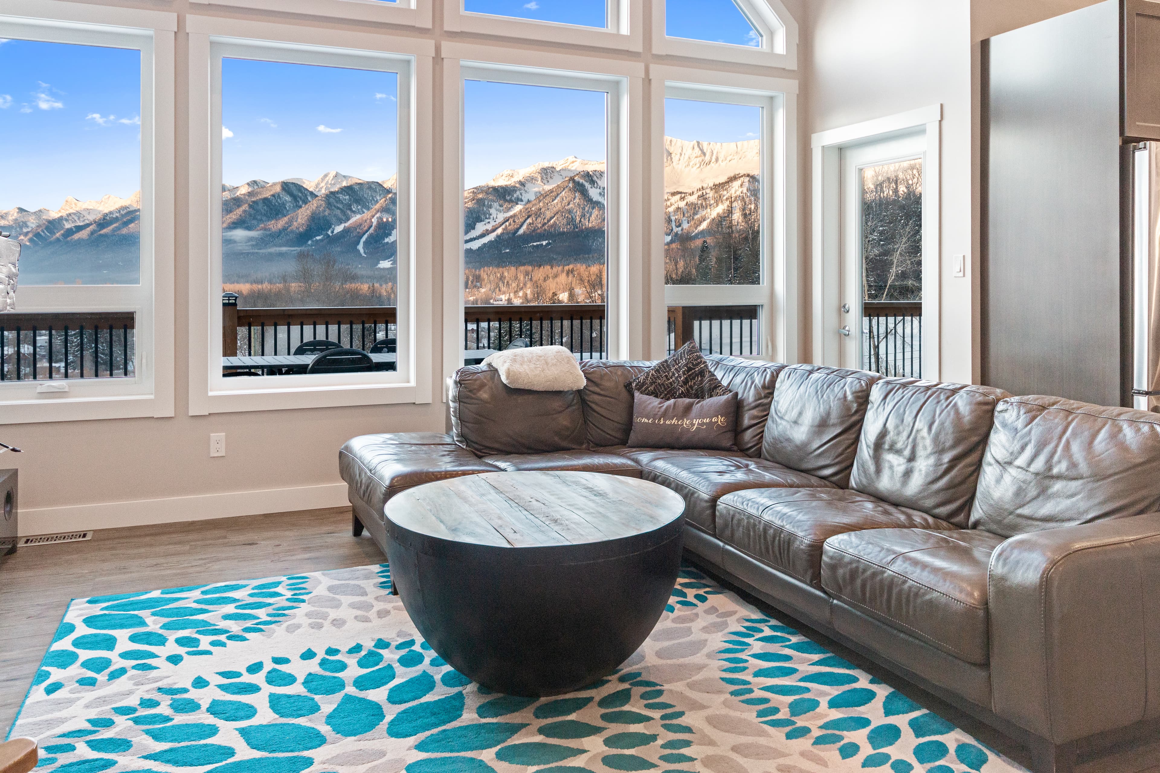 Living room with floor-to-ceiling windows framing the snow-covered ski runs of Fernie Alpine Resort across the valley