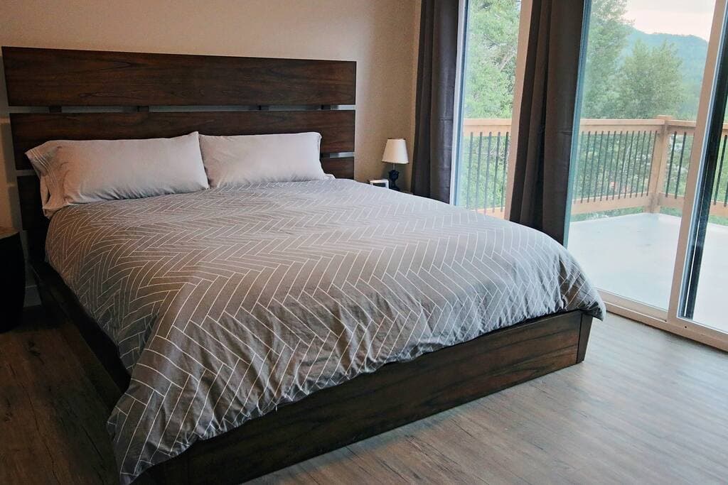 Main-floor primary bedroom: king bed with wood-slat headboard and sliding glass doors to the deck